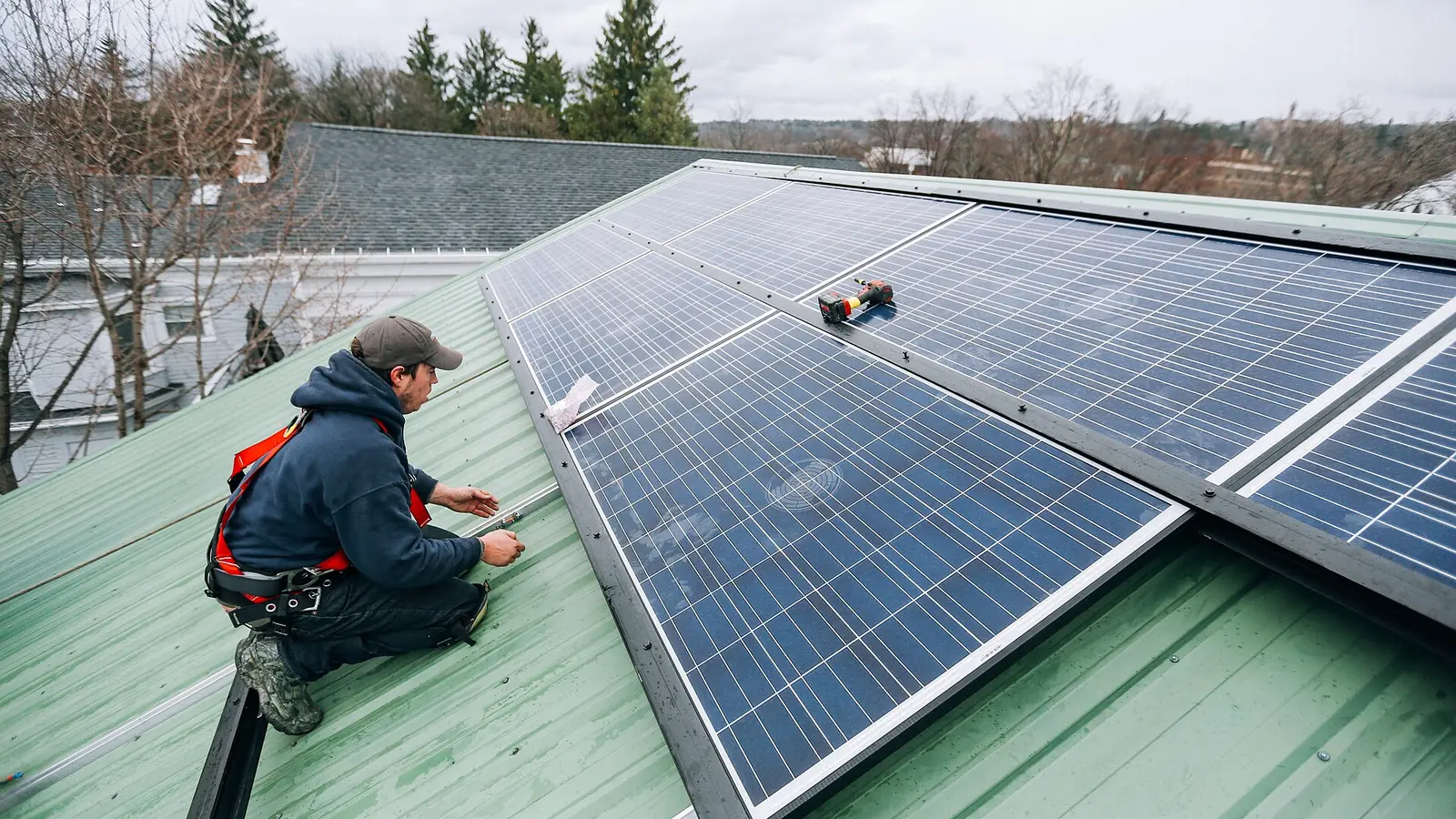 Tehnicieni care instalează panouri fotovoltaice pe acoperișul unei case